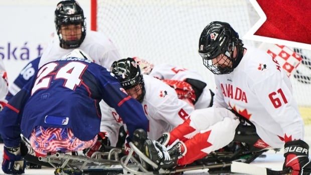 Some Para Ice Hockey players are seen fighting for a puck.