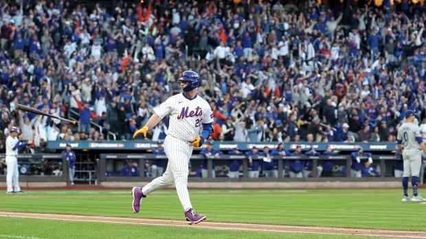 A men's baseball player rounds the bases after a home run.