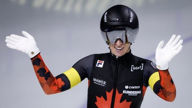 A women's speed skater waves her hands in celebration.