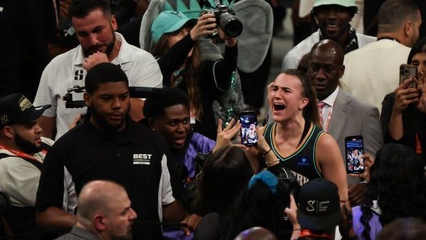 A woman basketball player is surrounded by fans.