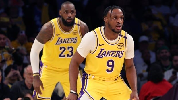 Two men's basketball players are shown standing with their hands at the sides.