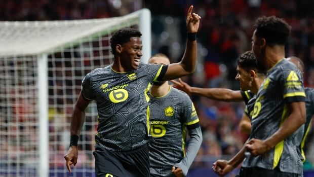 A men's soccer player celebrates with teammates.