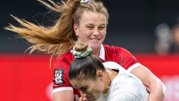 A women's rugby player completes a tackle.