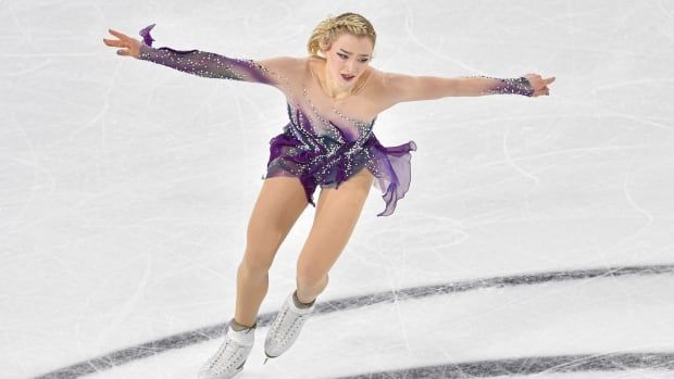 A women's figure skater stretches out her hands while skating.