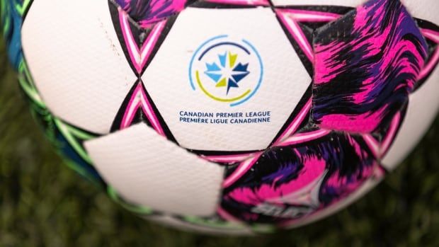 A soccer ball with purple and pink graphics and a red and blue logo in the middle.