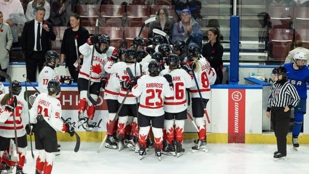 A women's hockey team celebrates near the glass after a win.