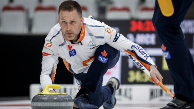 A male curling skip delivers a stone with his right hand during a game.