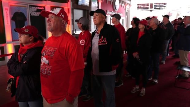 A group of baseball fans wait in a line.