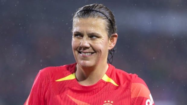 A woman soccer player smiles.