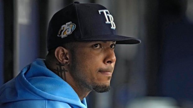 A closeup of a male baseball player sitting in a dugout.