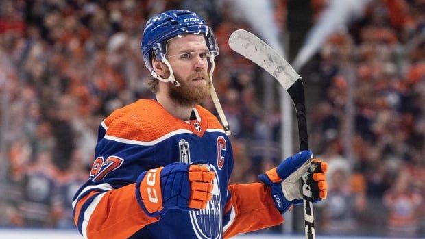 A male hockey player in an orange and blue jersey. 