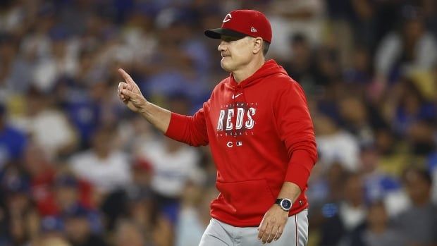 A men's baseball manager motions as he enters the field.