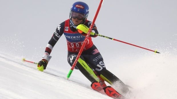 A women's alpine skier navigates a gate during a race.