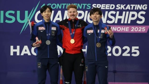 Three men's speed skaters hold their medals while posing together for a photograph.