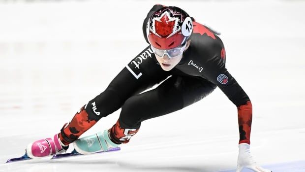 A speed skater touches the ice as she makes a turn.