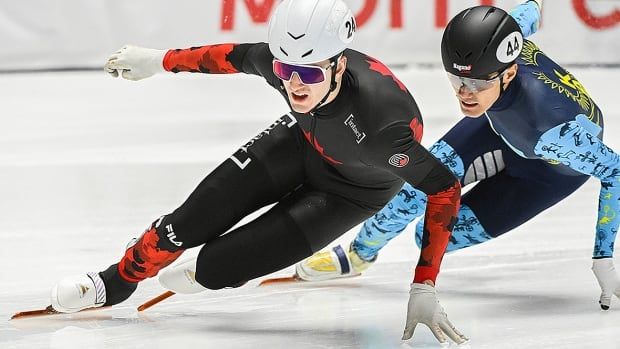 With his left hand touching the ice, Canadian men's speed skater skates ahead of his opponent during a short track World Cup race.