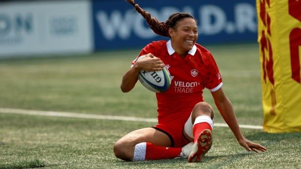 A rugby player smiles while scoring a try.