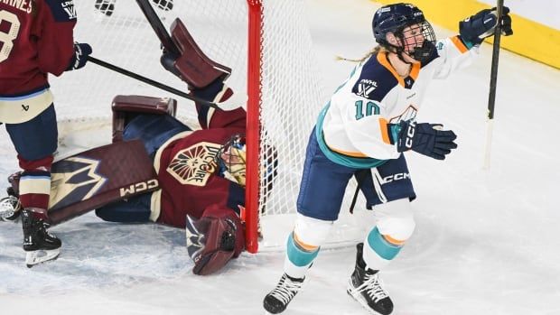 Female hockey player celebrates goal on ice. 