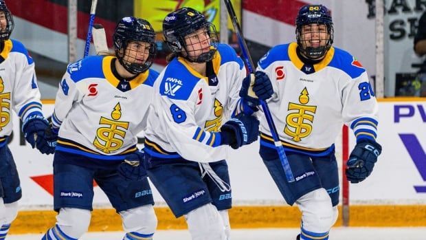 A group of hockey players celebrate on the ice.