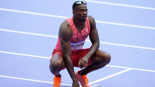 Male sprinter kneels down on track after race. 