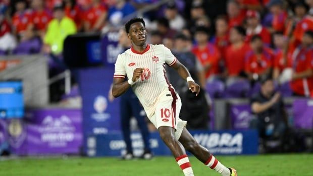 A male soccer player running on the turf during a soccer match.