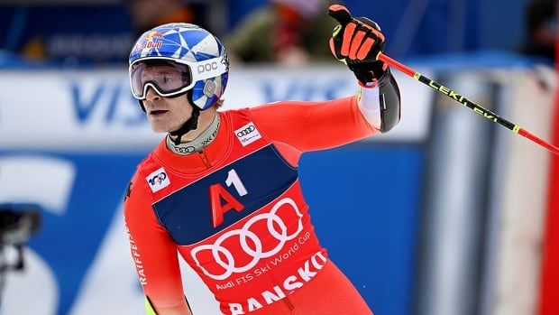 Holding a ski pole in his left hand, Swiss skier raises that arm while turning to look at his finishing time in a men's giant slalom World Cup race in Bulgaria.