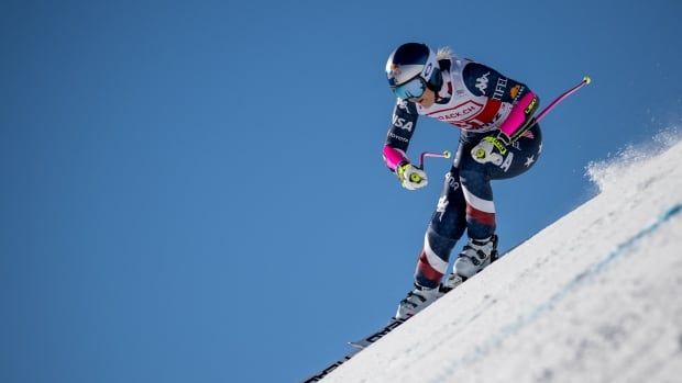 A women's alpine skier competes on a steep ski slope.