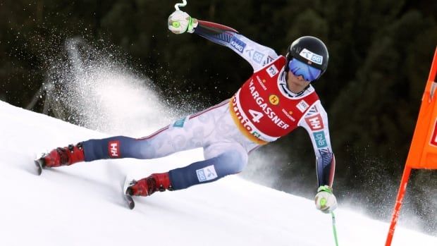 A male alpine ski racer speeds down a slope.