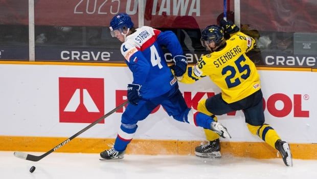 Two male ice hockey players battling for the puck.