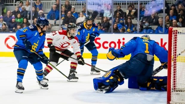 Female hockey players around the crease.