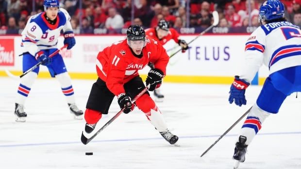 Male hockey player stick handles the puck.