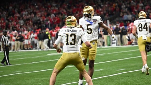 Two male football player celebrating together on the field.