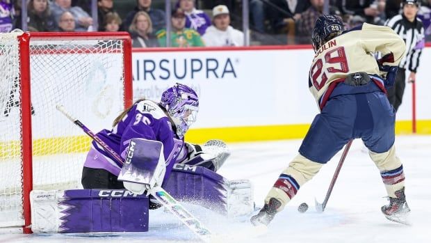 A player tries to score on a goalie on the ice.