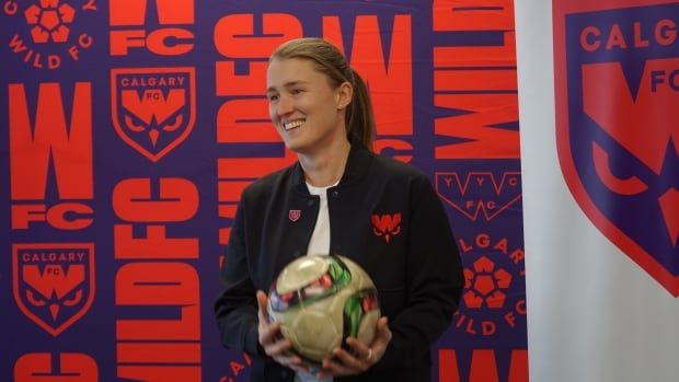 A woman is pictured holding a soccer ball