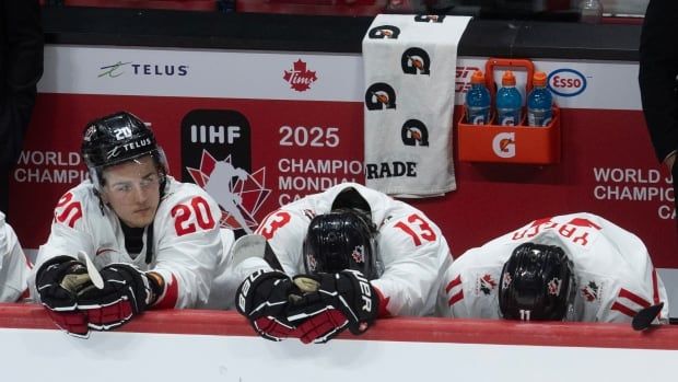 A group of hockey players on a same team sitting together and showing their disappointment after the result.