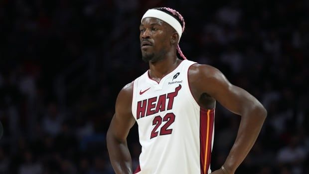 A male basketball player stands on the court.