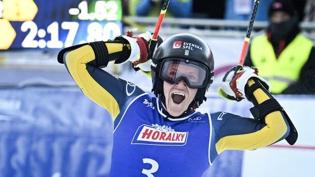 With ski poles in each hand, a beaming Sweden women's athlete raises both arms after winning a giant slalom World Cup race in Jasna, Slovakia.