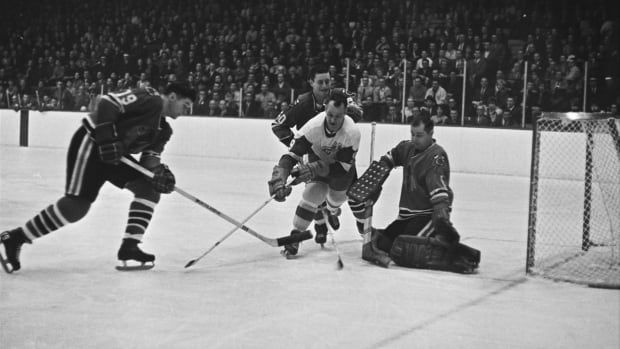 A black and white image of men playing hockey without helmets. 