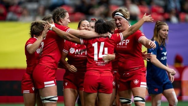 A women's rugby team celebrating together after a play.