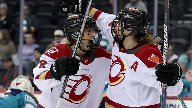 Women's hockey player celebrates with teammate after goal