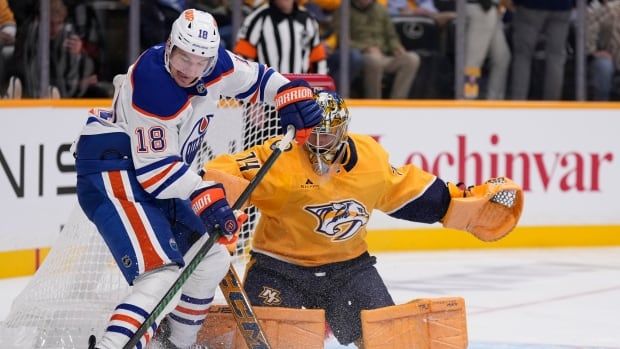 Edmonton Oilers left wing Zach Hyman (18) tries to get the puck past Nashville Predators goaltender Juuse Saros (74) during the first period of an NHL hockey game Thursday, Oct. 17, 2024, in Nashville, Tenn. 