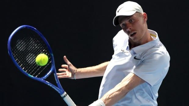 A men's tennis player returns a shot.