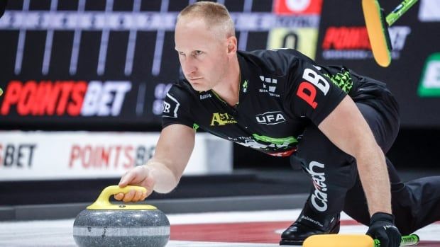 A male curling player delivering a stone.