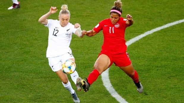 Two soccer players kick at a ball during a game.