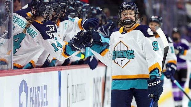 Women's hockey player celebrates goal with teammates