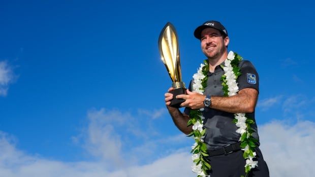 A male golfer poses his trophy with joy after clinching a victory.