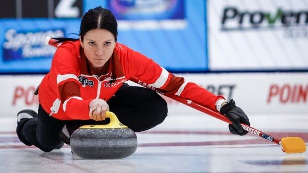 A female curling player makes a shot.