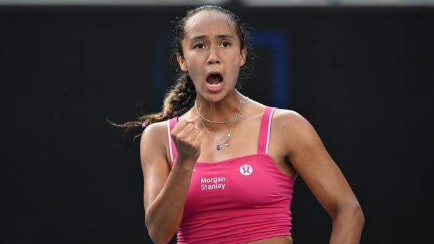 A women's tennis player shouts and pumps her fist in celebration.