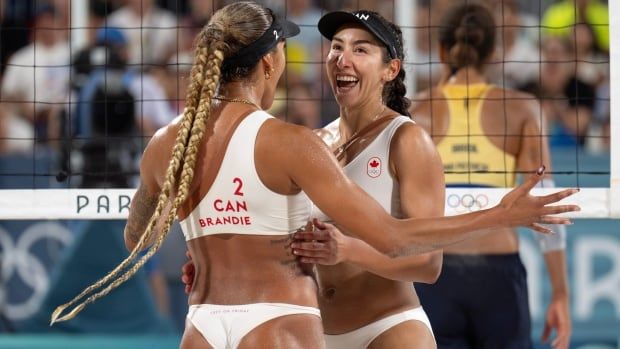 Two female beach volleyball players celebrates with joy and hug after a point.