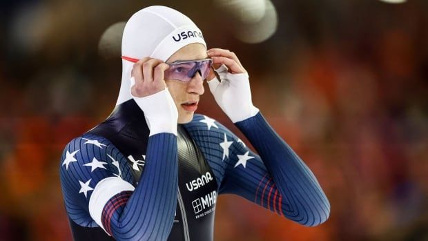 A men's speed skate adjusts his eyeglasses.